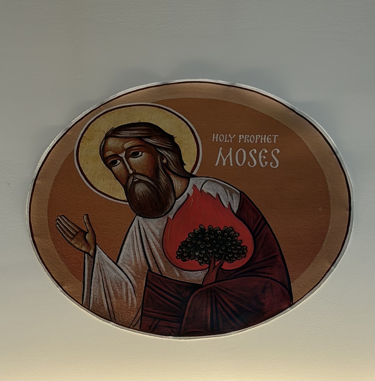 Circular church icon of the prophet Moses holding a red burning bush, surrounded by a golden halo.