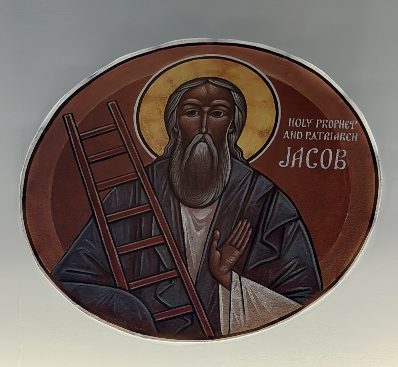 Circular church icon of the patriarch Jacob beside a ladder, with a gold halo against a red background.