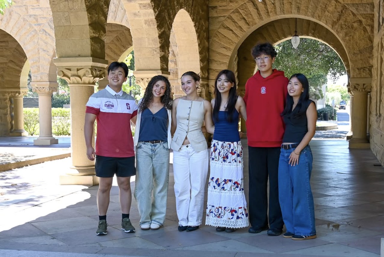 A group of students standing together beneath stone arches during the summer humanities program.